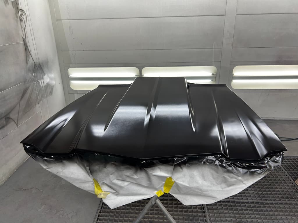 The same cowl induction hood in the spray booth after a coat of black epoxy primer