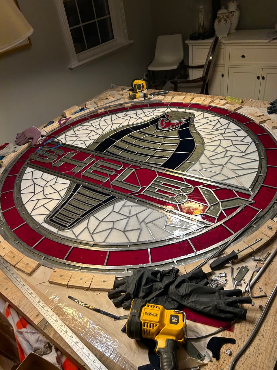 The full circular Shelby panel on the work table, red outer ring and SHELBY lettering across a snake on a white background